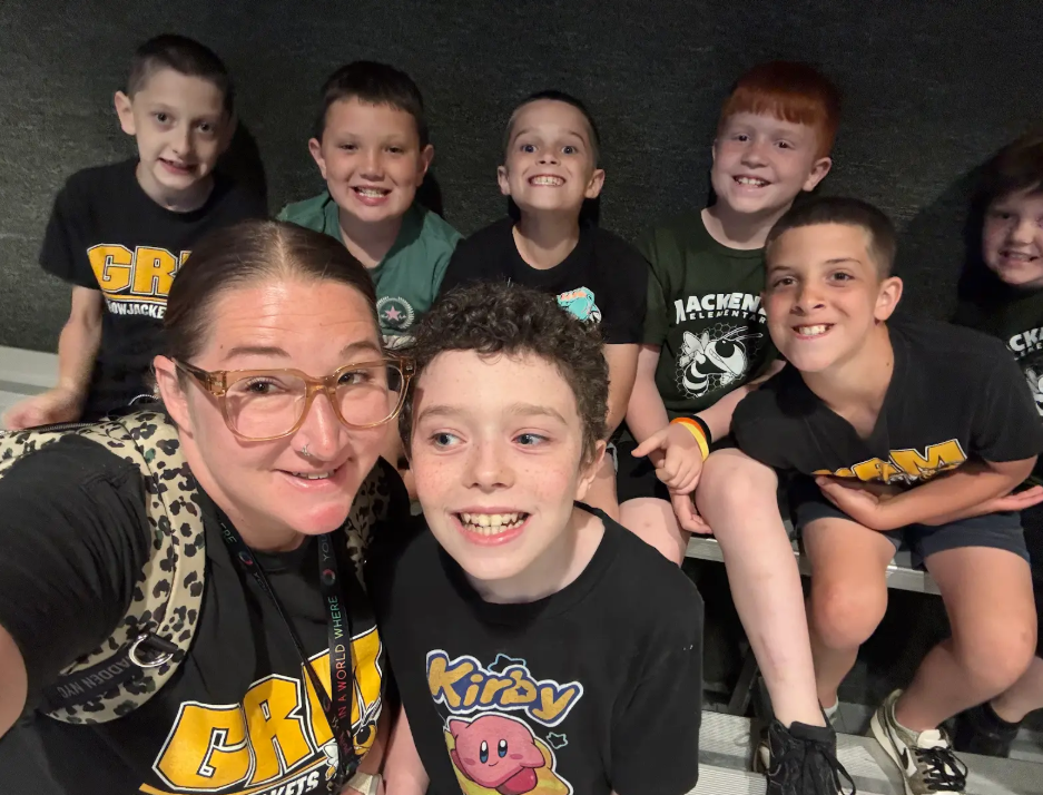 Image of a teacher taking a selfie with a group of students on a field trip