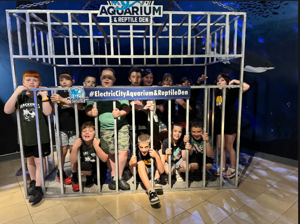A group of students pose in a shark cage at an Aquarium