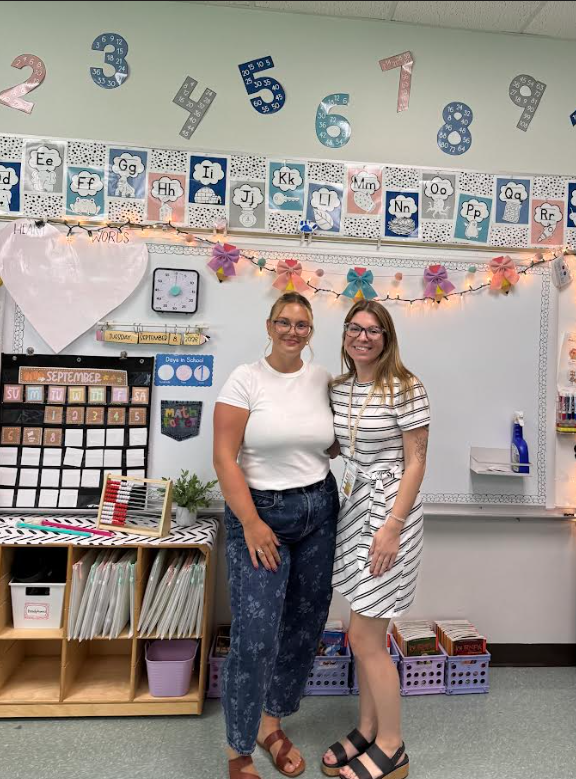 Image of two adults posing in front of a classroom whiteboard