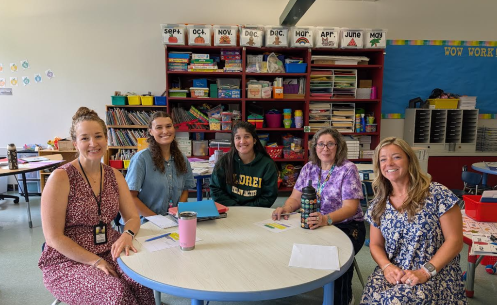 Image of a team of 5 teacher sitting at a round table