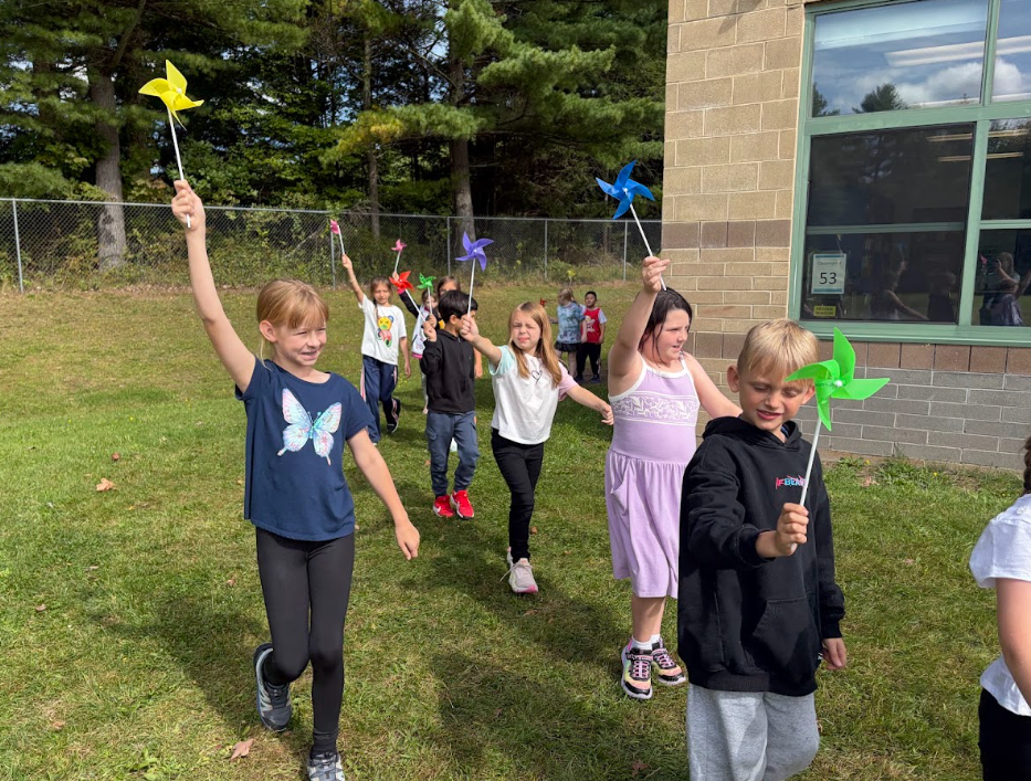 Image of student parading with colorful pinwheels in their hands