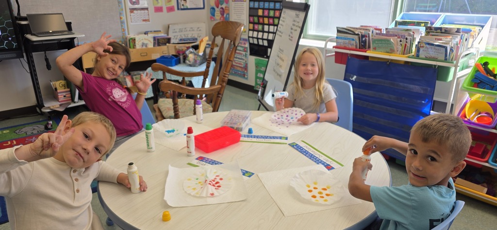 Image of children sitting at a round table make dot inspired artwork