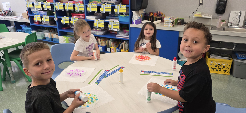 Image of children sitting at a round table make dot inspired artwork