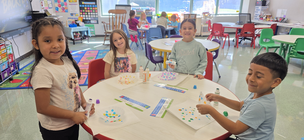 Image of children sitting at a round table make dot inspired artwork