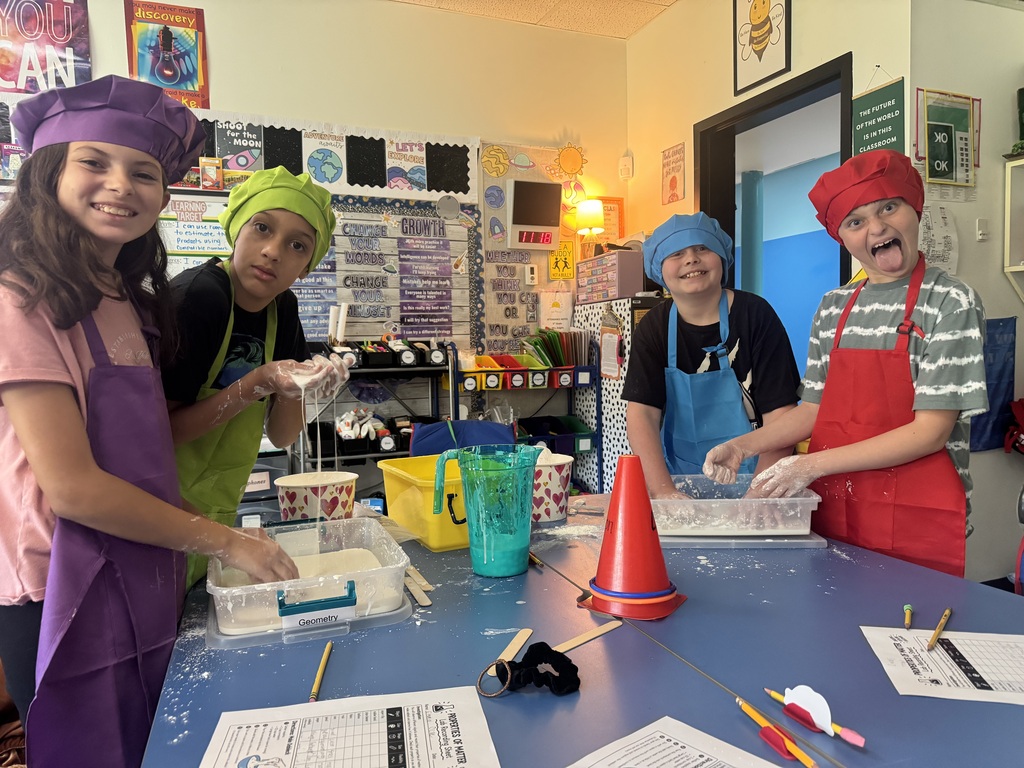 Students wear colorful aprons & hats while participating in a science lab on the Law of Conservation of Matter by making OOBLEK.