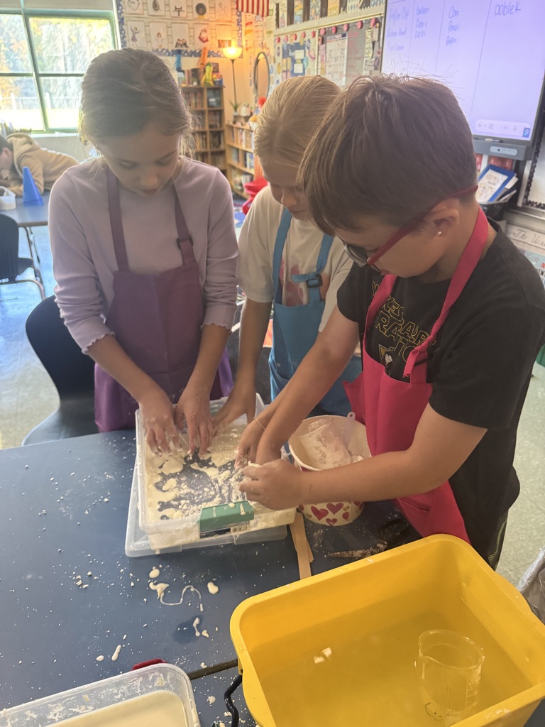 Students wear colorful aprons while participating in a science lab on the Law of Conservation of Matter by making OOBLEK.