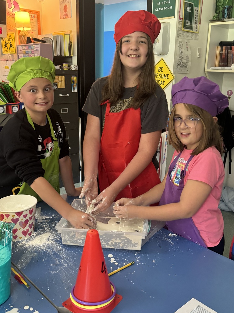 Students wear colorful aprons & hats while participating in a science lab on the Law of Conservation of Matter by making OOBLEK.