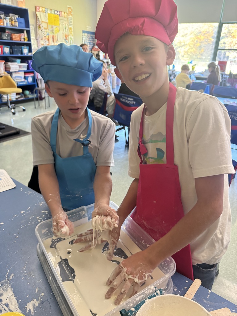 Students wear colorful aprons & hats while participating in a science lab on the Law of Conservation of Matter by making OOBLEK.