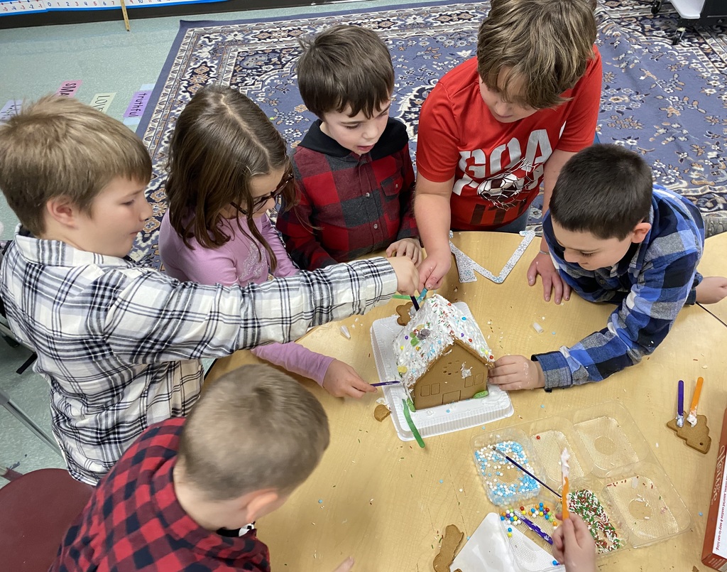 image of children surrounding a table as they work together to construct a gingerbread house