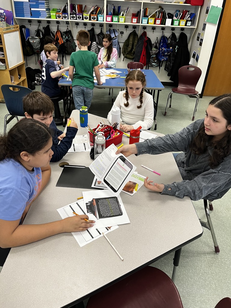 Image of students sitting at a white table with documents in front of them