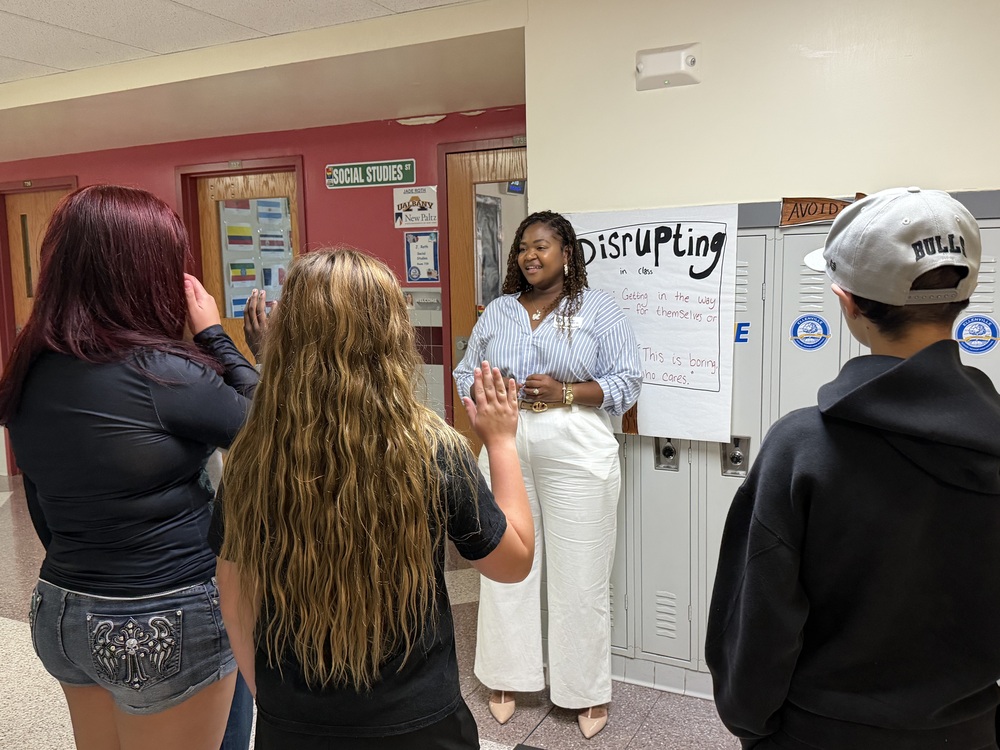 Principal Galloway speaks to a group of students in a hallway