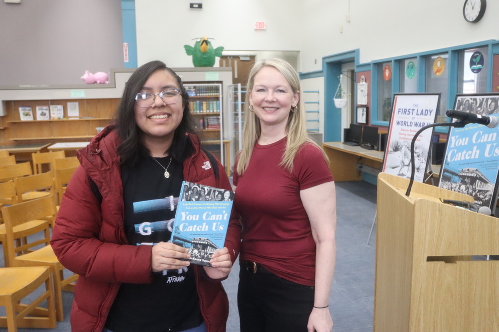 Student receives book from author Shannon McKenna Schmidt