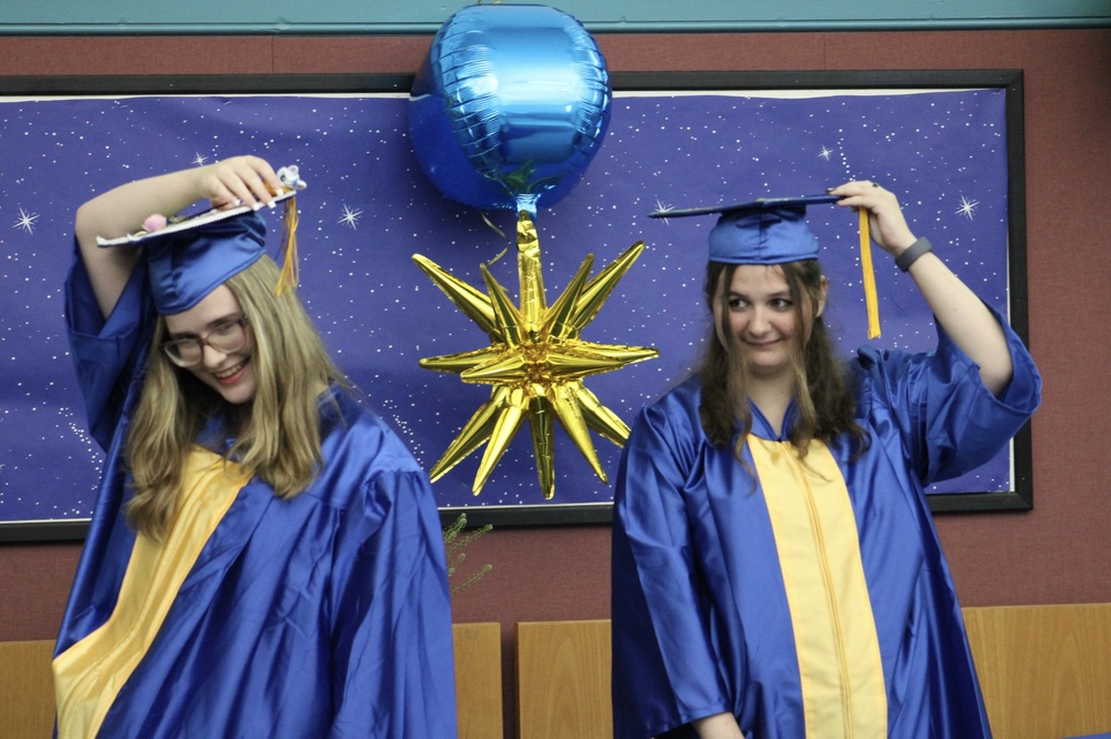 Two graduates turn the tassels on their caps