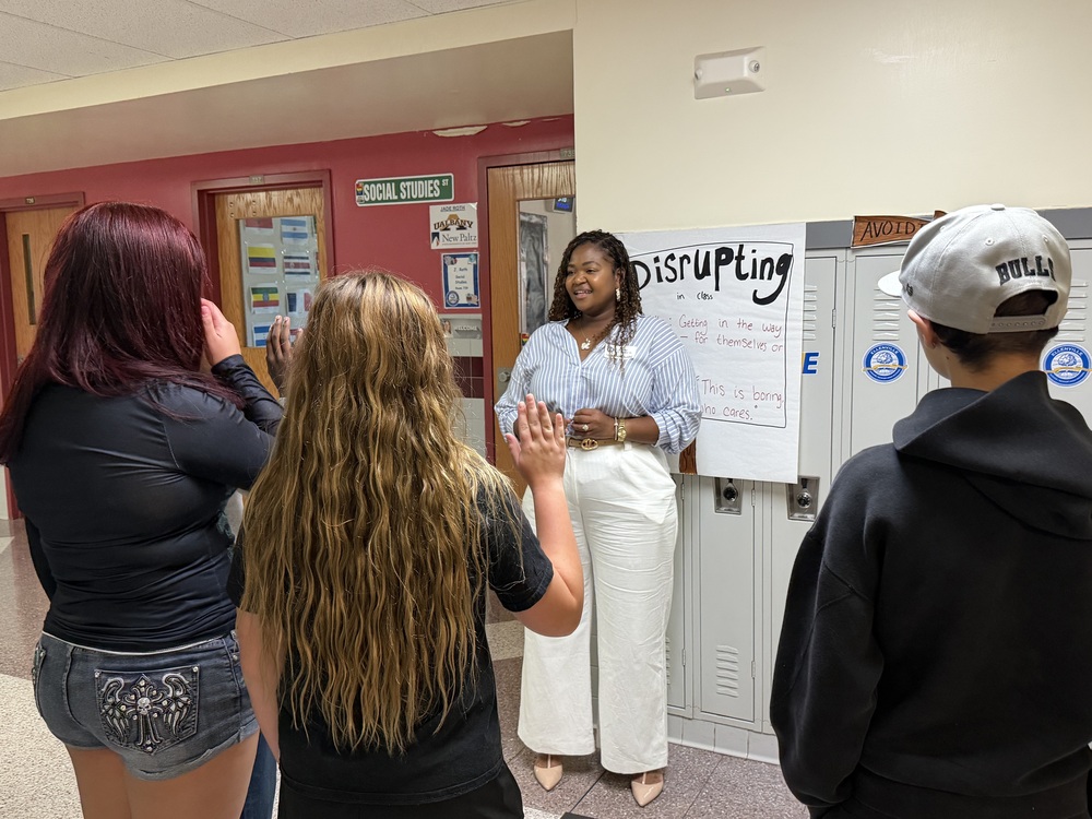 Principal Galloway speaks to a group of students in a hallway