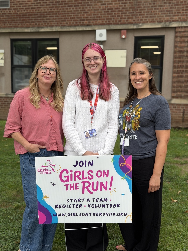 Three girls on the run coaches stand behind a sign asking girls to join