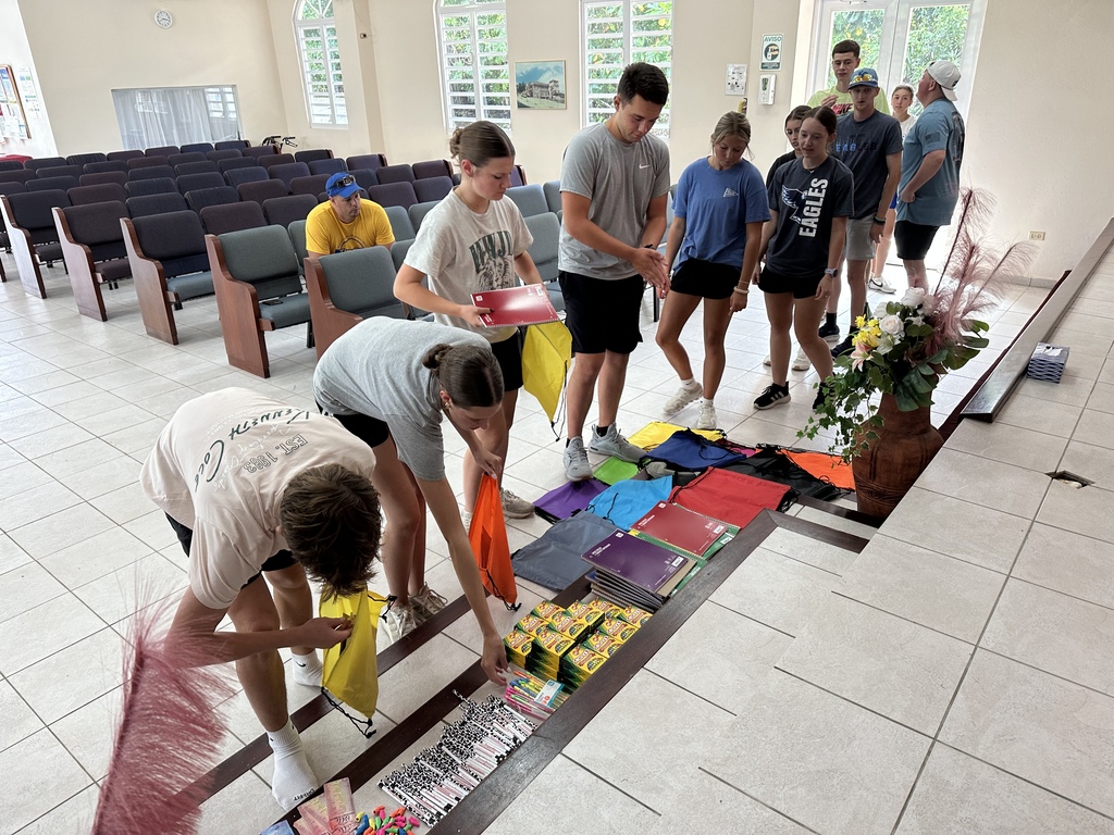A group of people in a church setting, some bent over a table with colorful items, others standing.