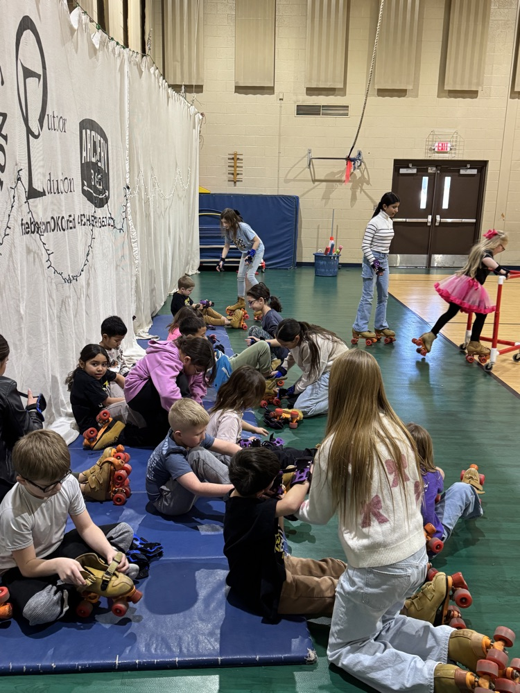 4th & 5th grade Leadership students helping put on skates in PE.