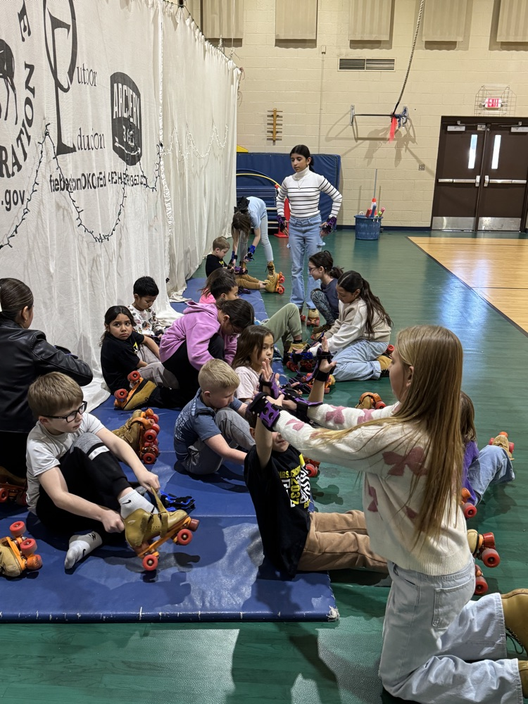 4th & 5th grade Leadership students helping put on skates in PE.