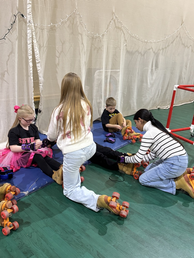 4th & 5th grade Leadership students helping put on skates in PE.
