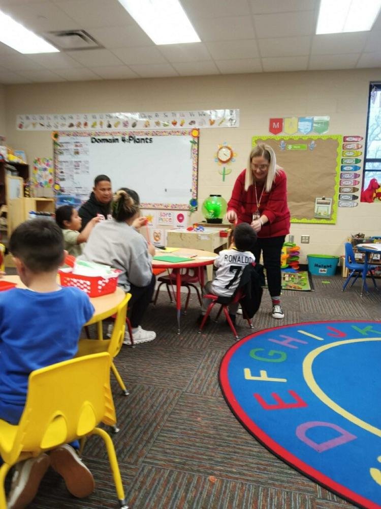 Ms. Aguilar helps students make a craft  