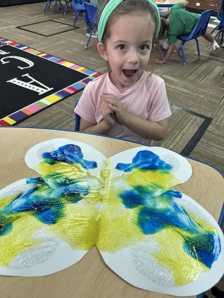 Little girl wearing a green headband & showing her painted butterfly