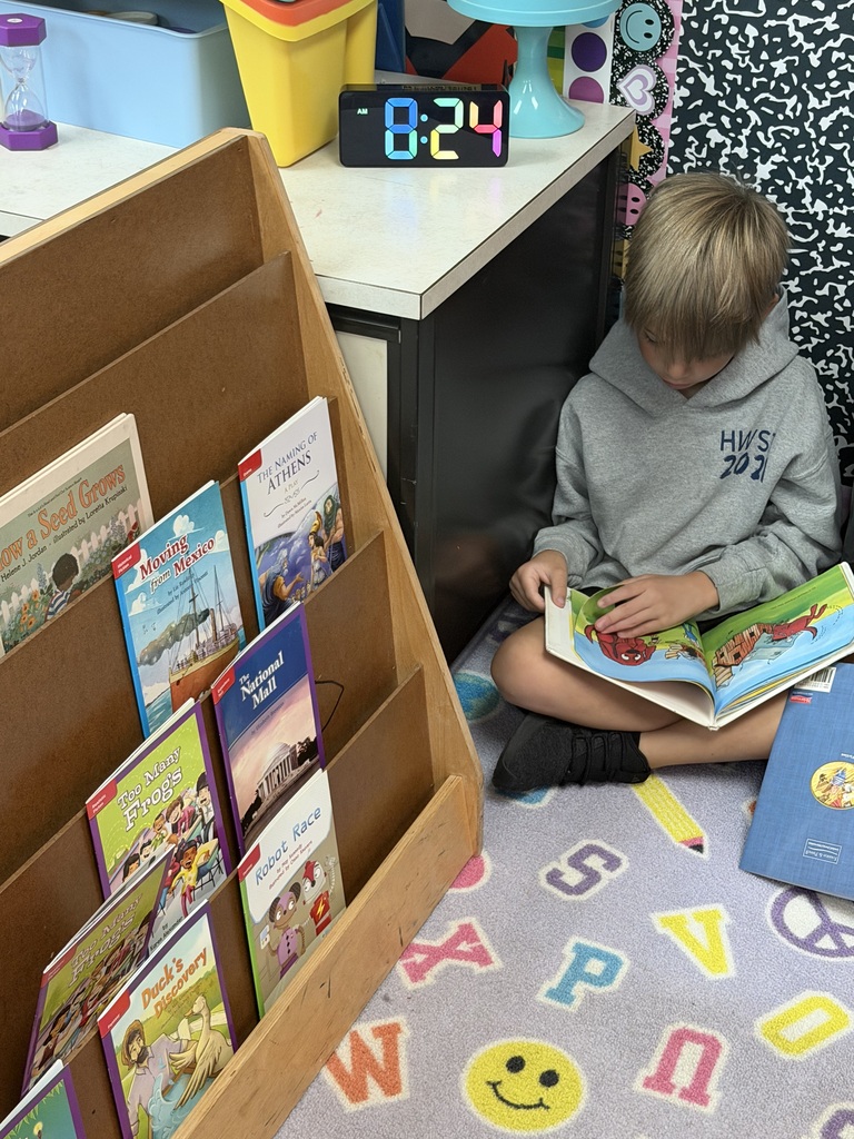 Young man sitting quietly by bookshelf reading