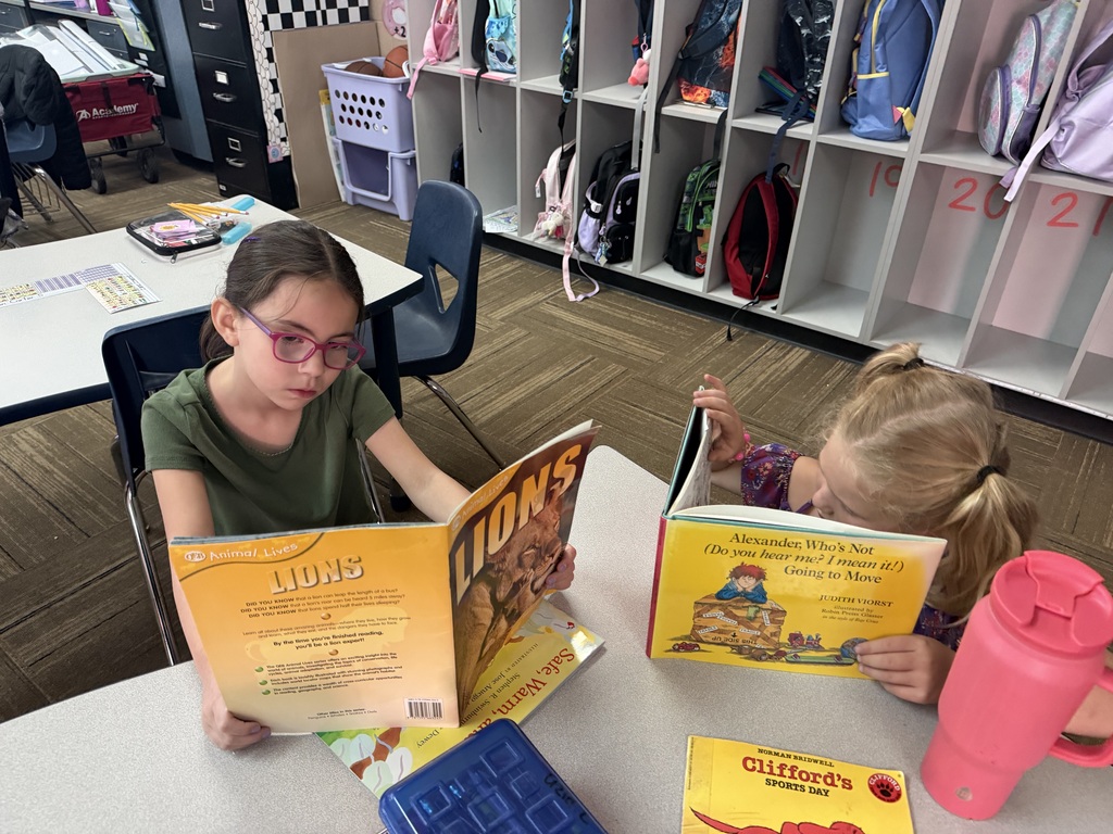 Two girls sitting next to each other reading