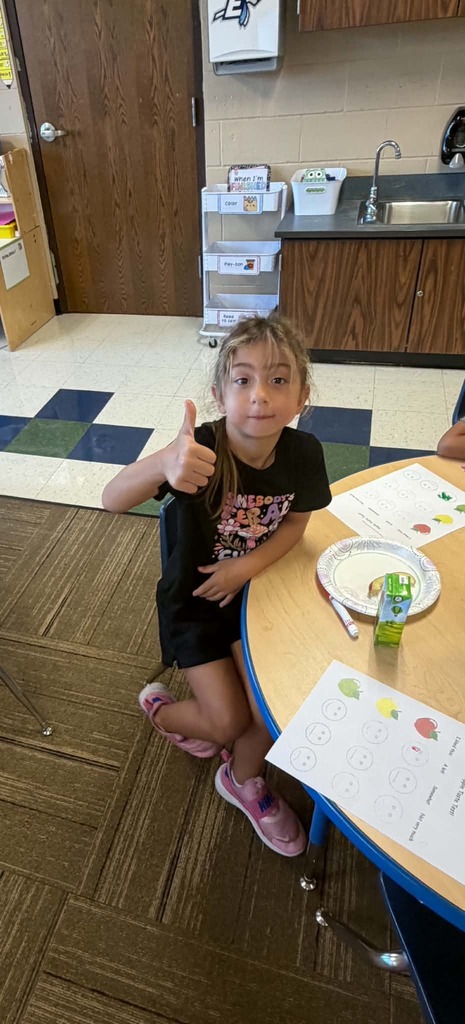 Children sitting at a table giving thumbs up or down