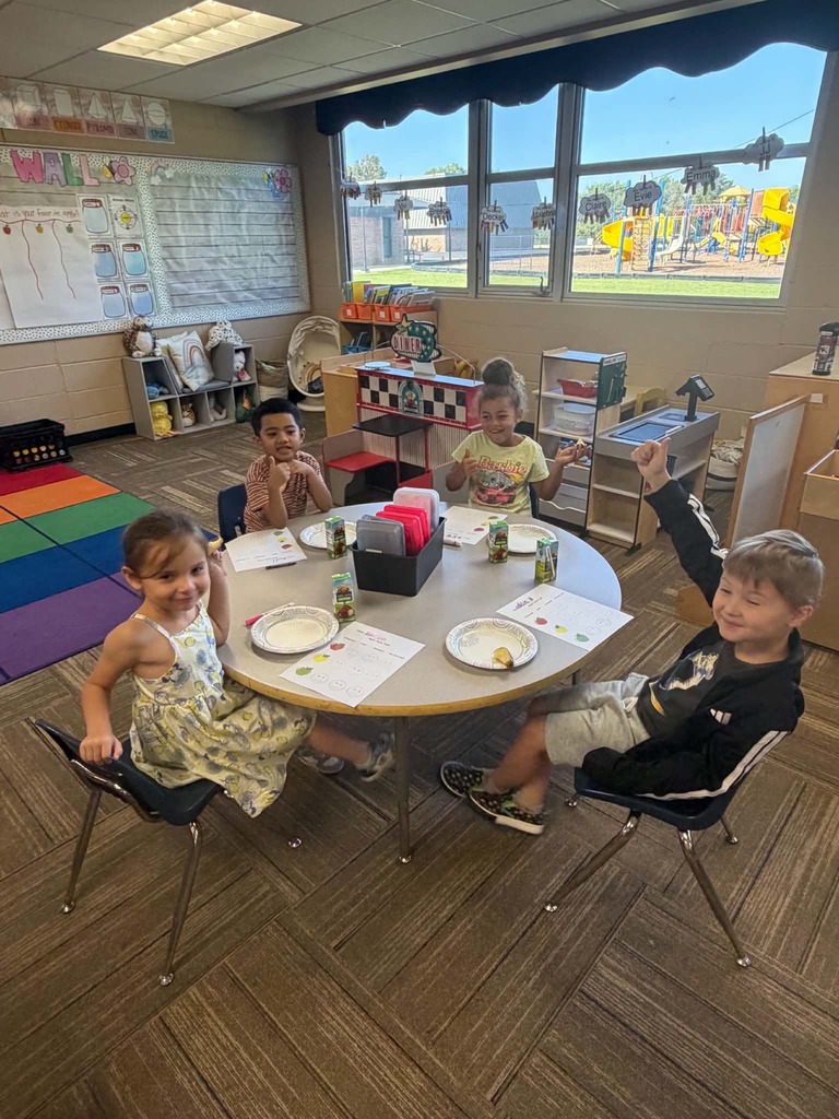 Children sitting at a table giving thumbs up or down