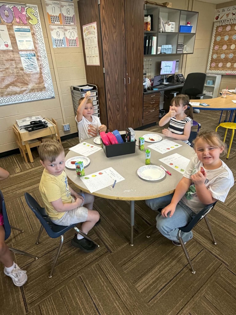 Children sitting at a table giving thumbs up or down