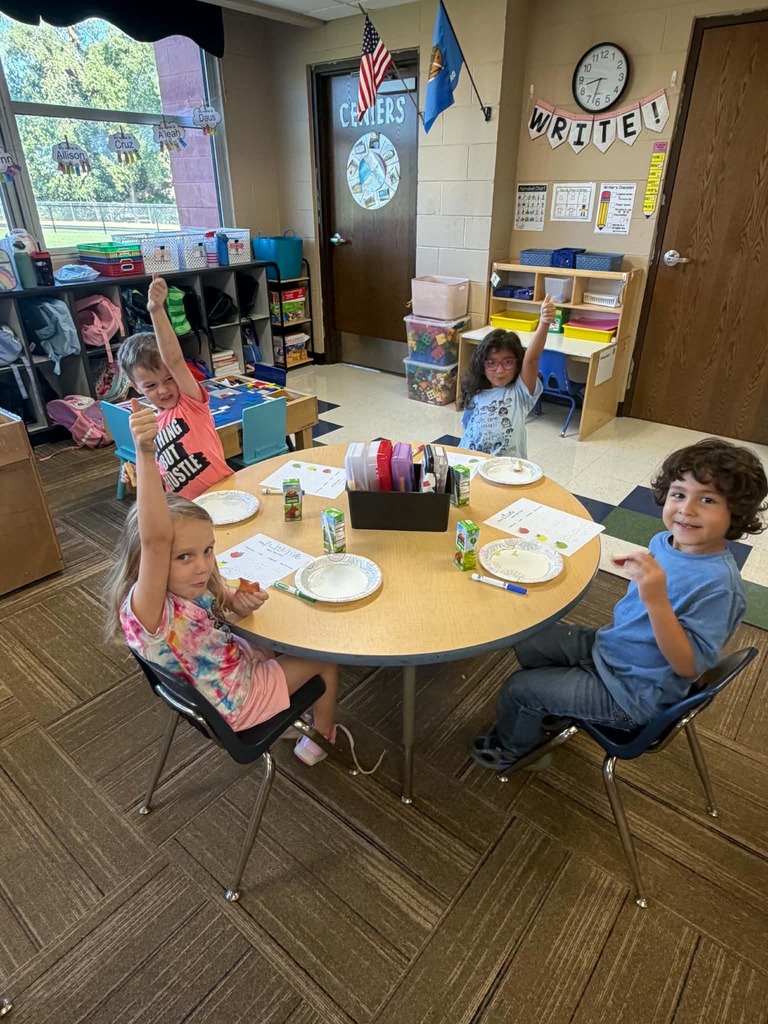 Children sitting at a table giving thumbs up or down