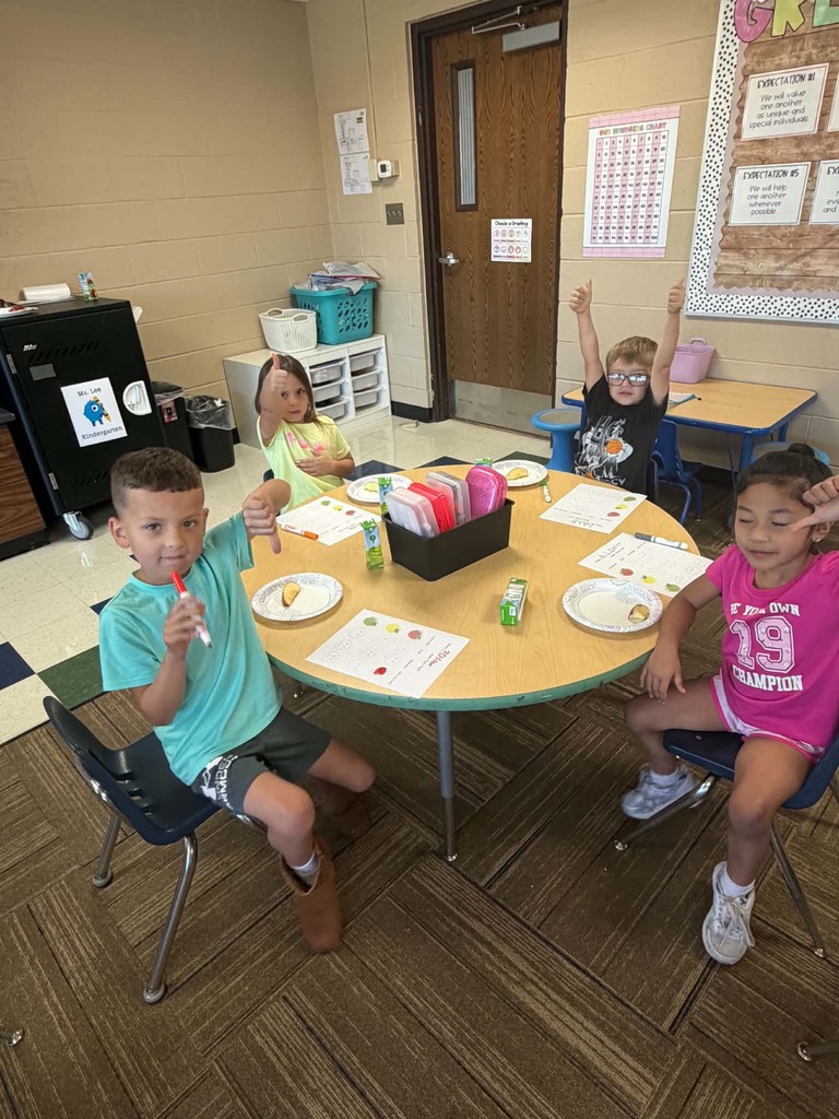 Children sitting at a table giving thumbs up or down