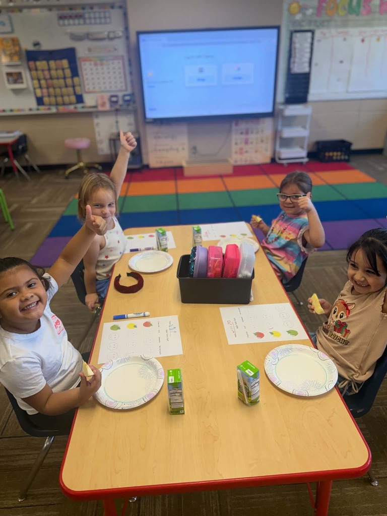 Children sitting at a table giving thumbs up or down