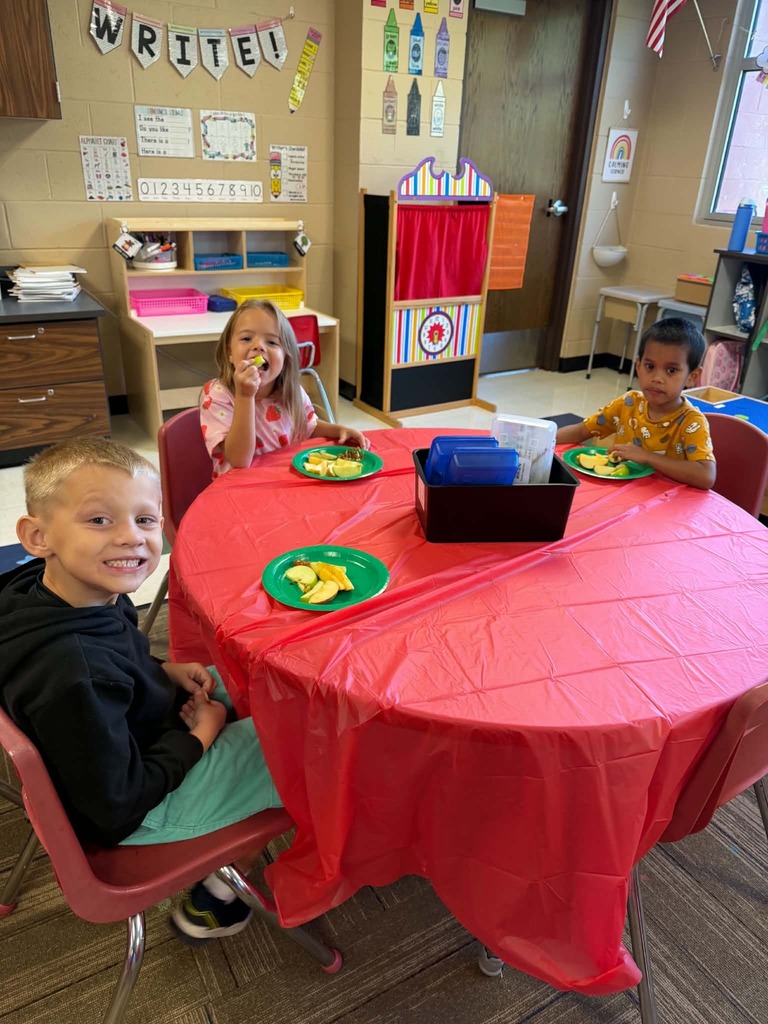 Children sitting at tables enjoying apple slices
