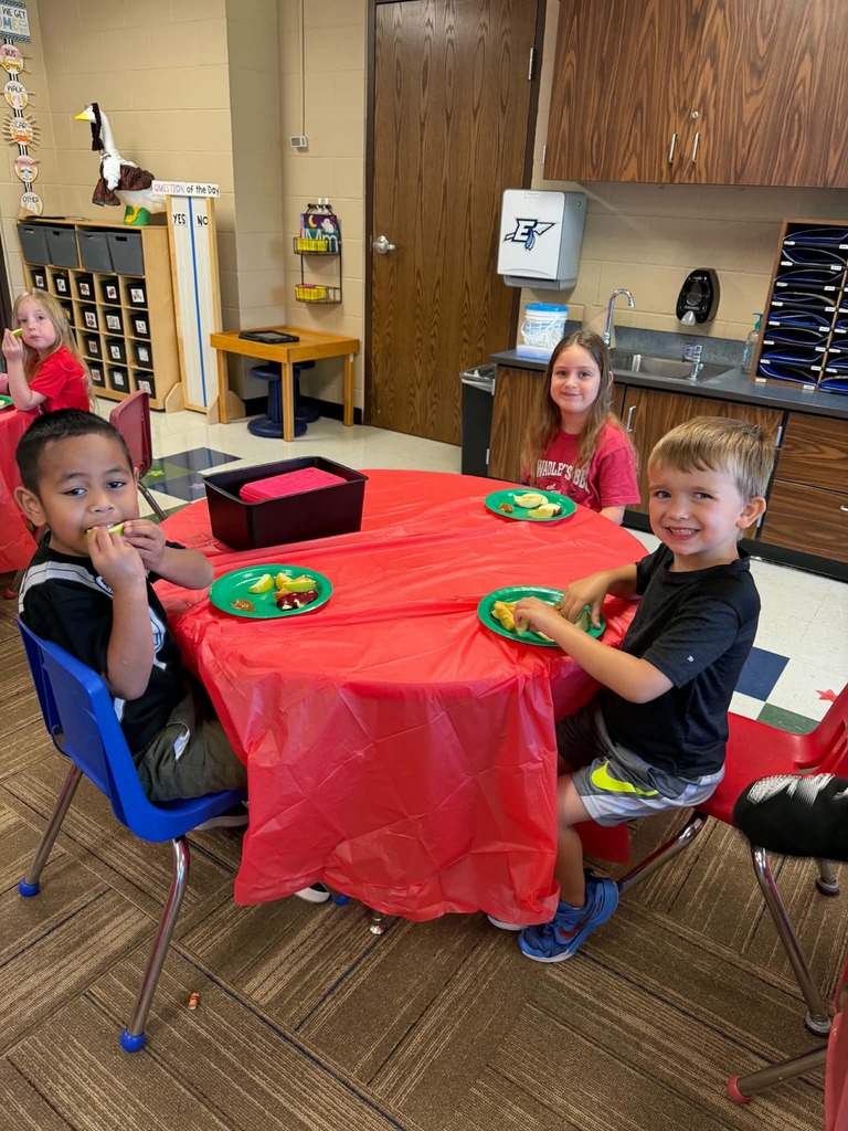 Children sitting at tables enjoying apple slices