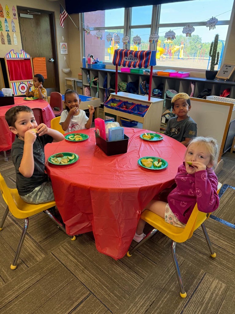 Children sitting at tables enjoying apple slices