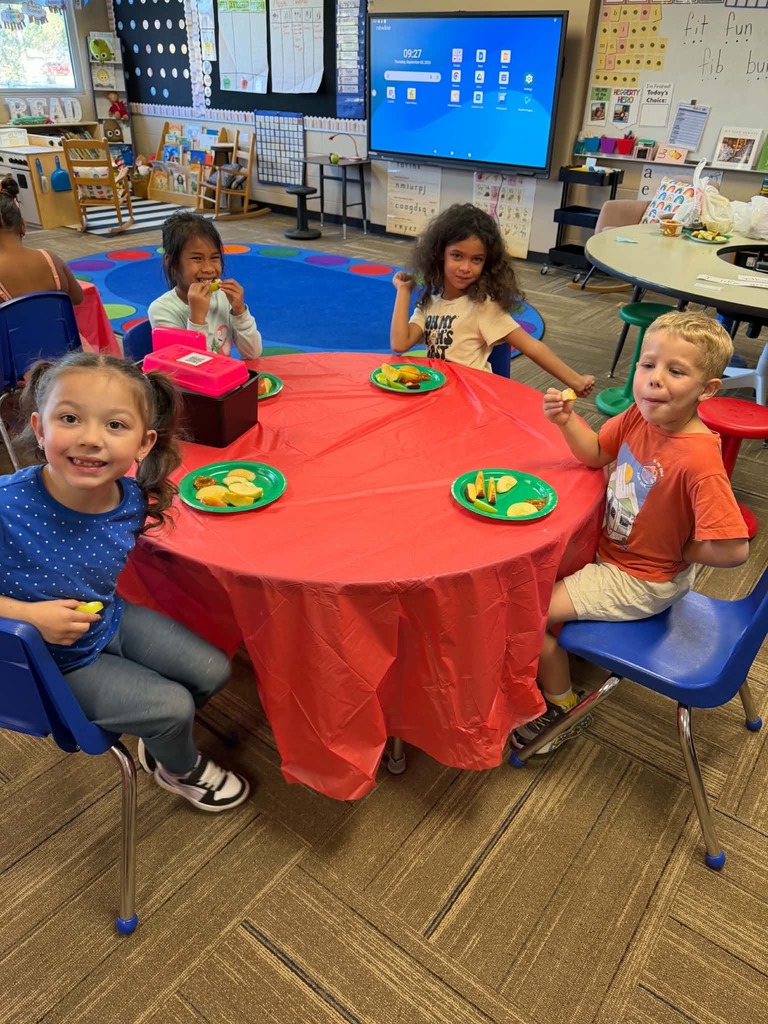 Children sitting at tables enjoying apple slices