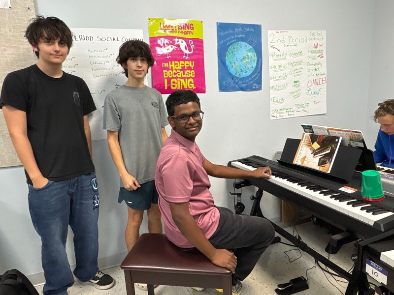 Three teenage boys around an electric piano