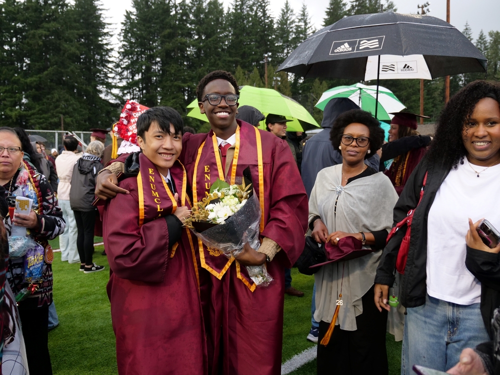 Two EHS graduates pose for a photo after the ceremony surrounded by family
