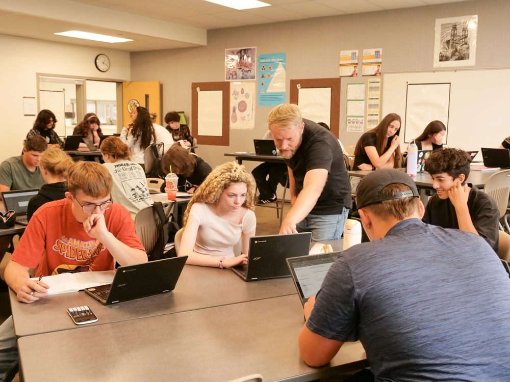 Adam Ihde, a national board certified math teacher at Enumclaw High School, works alongside students during a lesson that builds critical-thinking and collaboration skills.