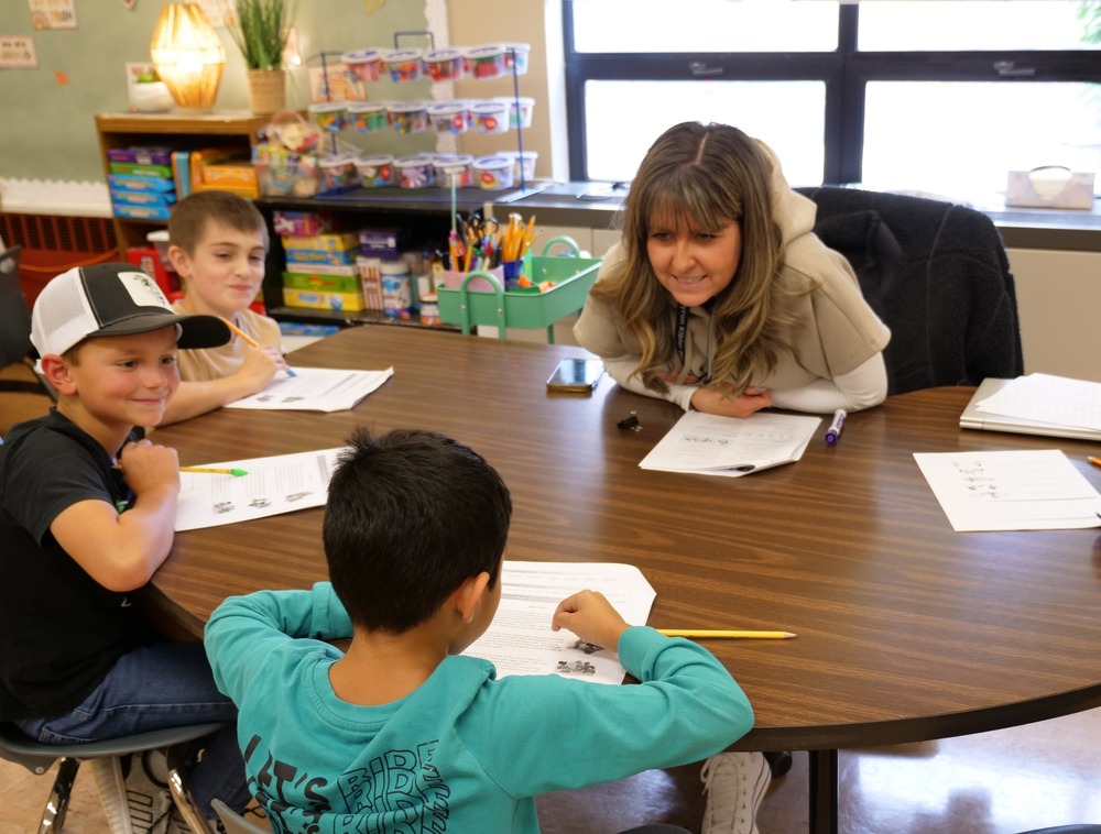 Students sitting around a small group table engaging in WIN time,  working on reading skills