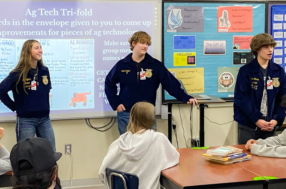 Three high school FFA students teach enumclaw middle school students a lesson on agricultural technology standing in front of classroom