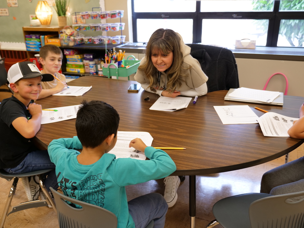 Students sitting around a small group table engaging in WIN time,  working on reading skills