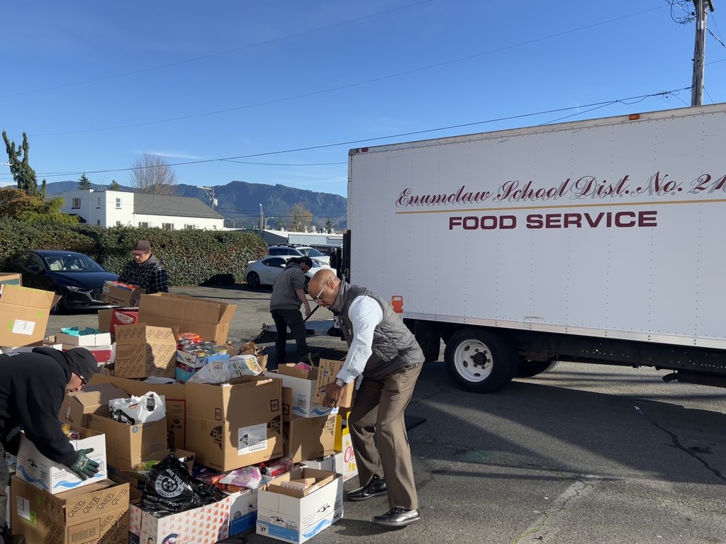 Enumclaw School District truck being unloaded with a big pile of donated food in front of the food bank