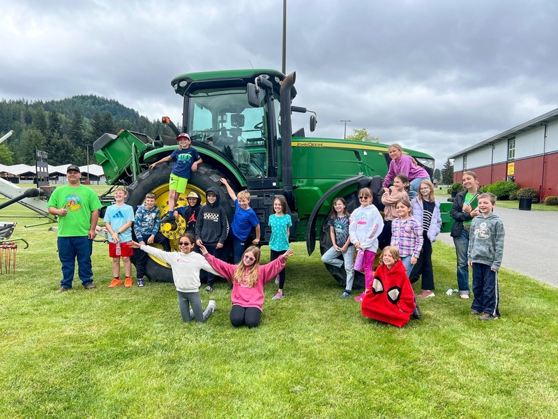 class posing in front of tractor