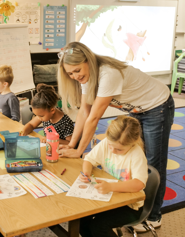 Mandy Simacek, Sunrise Elementary School kindergarten teacher leaning down to a table of students working on a project