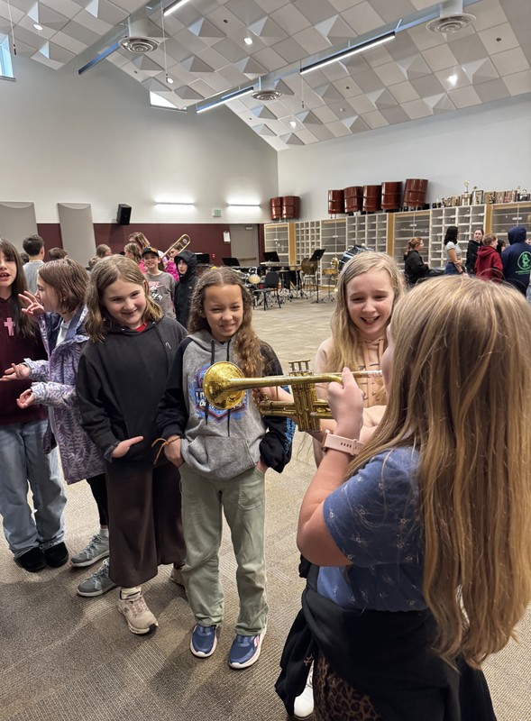 students watch another student try the trumpet