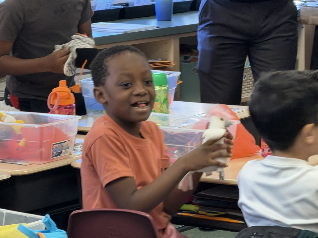 A students smiling and holding a stuffed bird. 