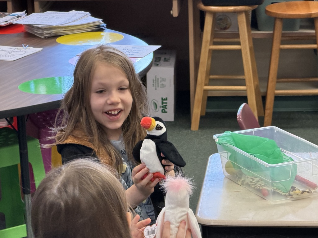 A students smiling and holding a stuffed bird. 
