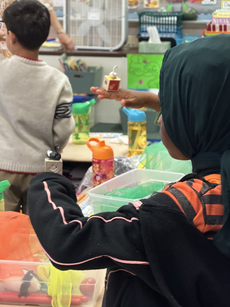 A student holding a block on the back of her hand that has a black swan on it.